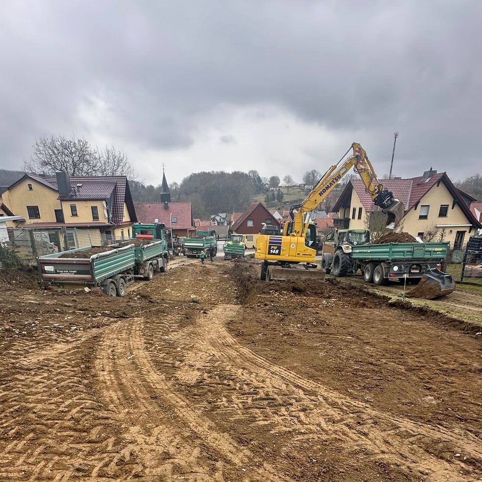 Bagger und Transportfahrzeuge bei Erdarbeiten im Wohngebiet